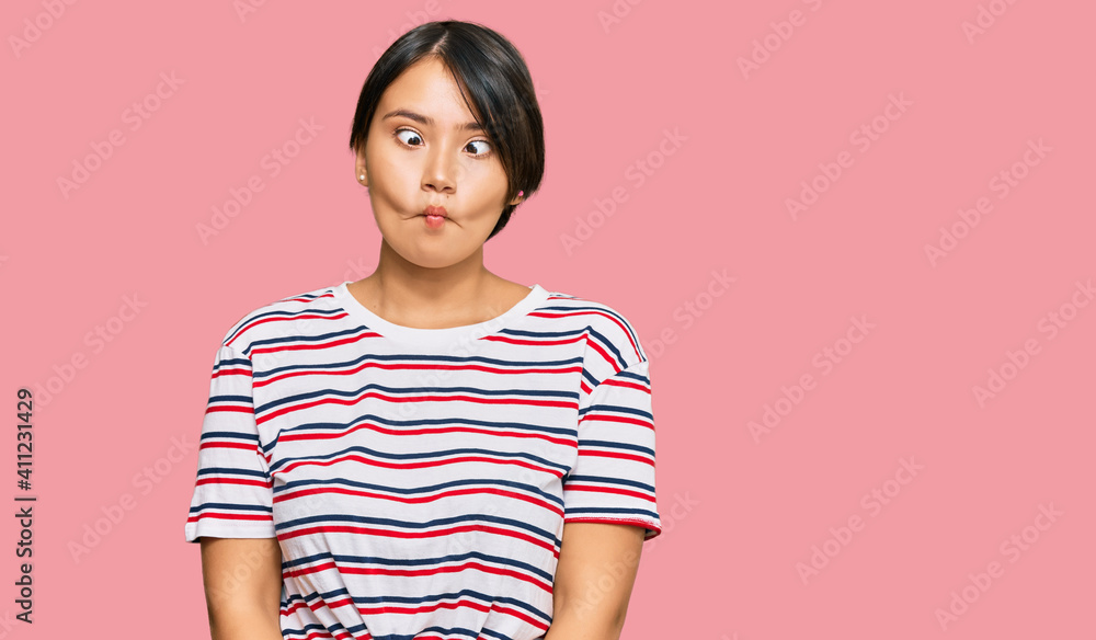 Beautiful young woman with short hair wearing casual clothes making fish face with lips, crazy and comical gesture. funny expression. Beautiful young woman with short hair wearing casual clothes making fish face with lips, crazy and comical gesture. funny expression.