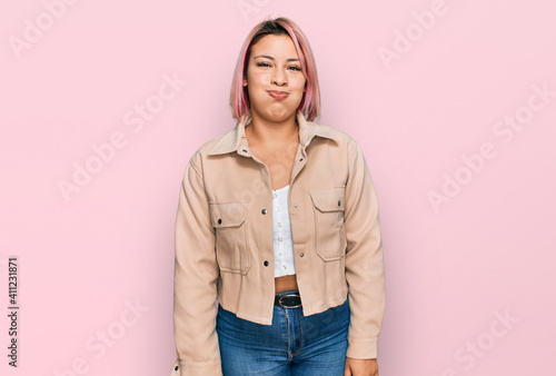 Hispanic woman with pink hair wearing casual clothes puffing cheeks with funny face. mouth inflated with air, crazy expression. © Krakenimages.com