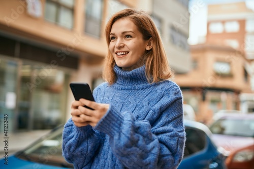 Wallpaper Mural Young caucasian girl smiling happy using smartphone at the city. Torontodigital.ca