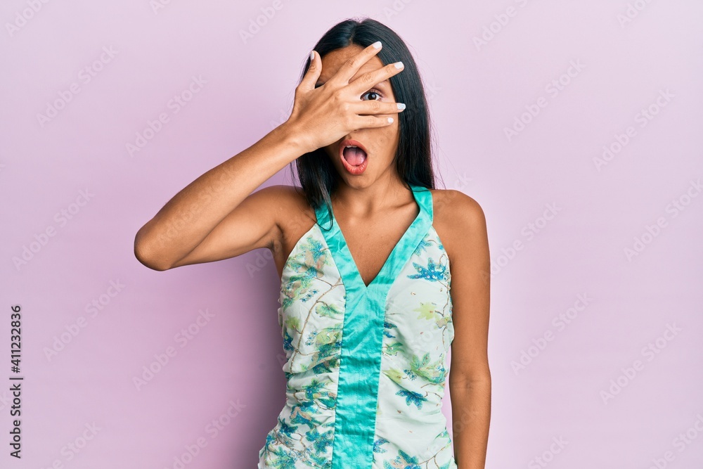 Young brunette woman wearing elegant summer shirt peeking in shock covering face and eyes with hand, looking through fingers afraid Young brunette woman wearing elegant summer shirt peeking in shock covering face and eyes with hand, looking through fingers afraid