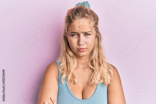 Young blonde girl wearing casual clothes skeptic and nervous  disapproving expression on face with crossed arms. negative person.
