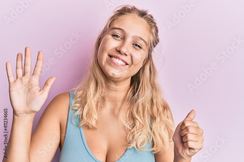 Young blonde girl wearing casual clothes showing and pointing up with fingers number six while smiling confident and happy.