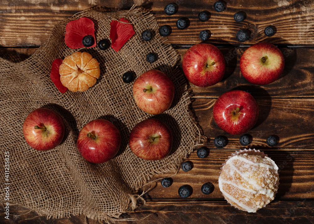 apples, muffin, blueberry, tangerine on wooden background 