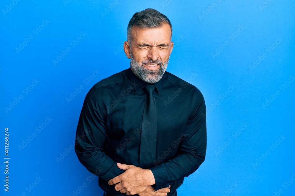 Middle age handsome man wearing business shirt and tie with hand on stomach because nausea, painful disease feeling unwell. ache concept. Middle age handsome man wearing business shirt and tie with hand on stomach because nausea, painful disease feeling unwell. ache concept.