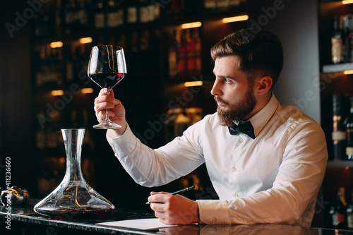 Young handsome man sommelier tasting red wine in cellar. photo