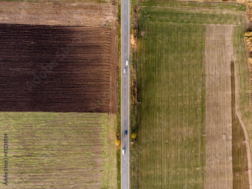 Aerial view of a road, in middle of colorful fields, sunny, autumn day - top down, drone shot