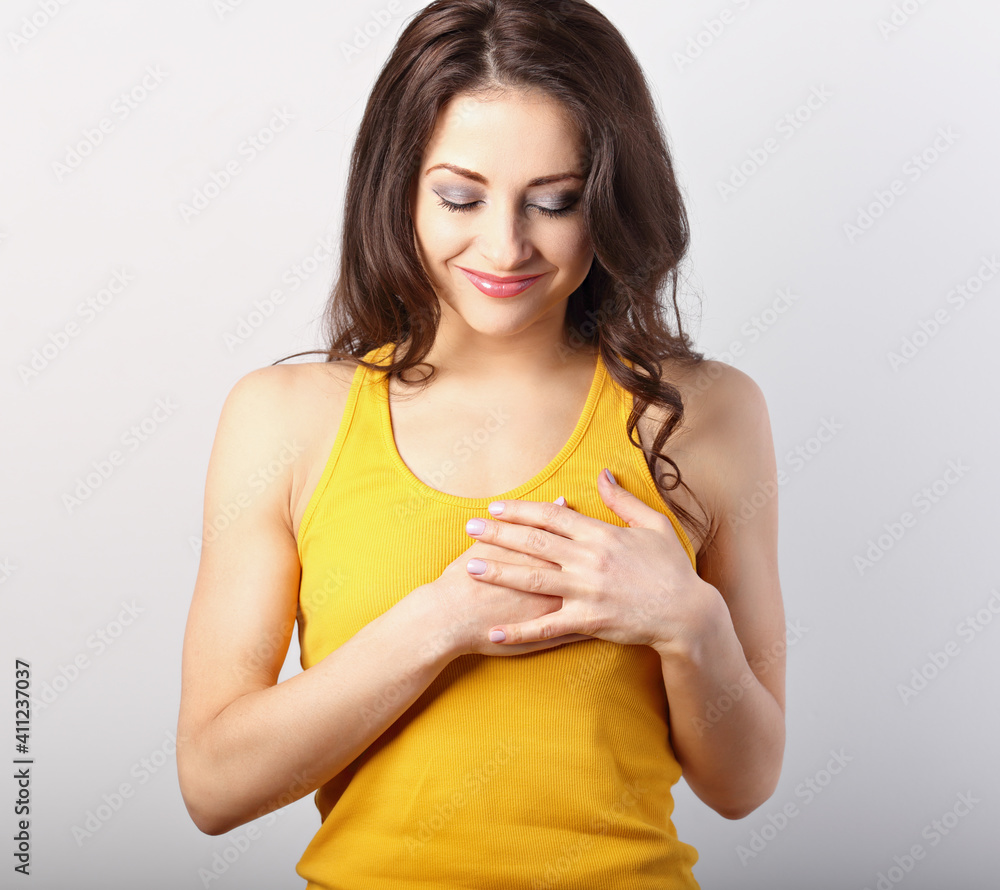 Beautiful woman in love holding herself chest and heart two hands with enjoying smiling face and thinking about emotion relationship on blue background. Closeup Beautiful woman in love holding herself chest and heart two hands with enjoying smiling face and thinking about emotion relationship on blue background. Closeup