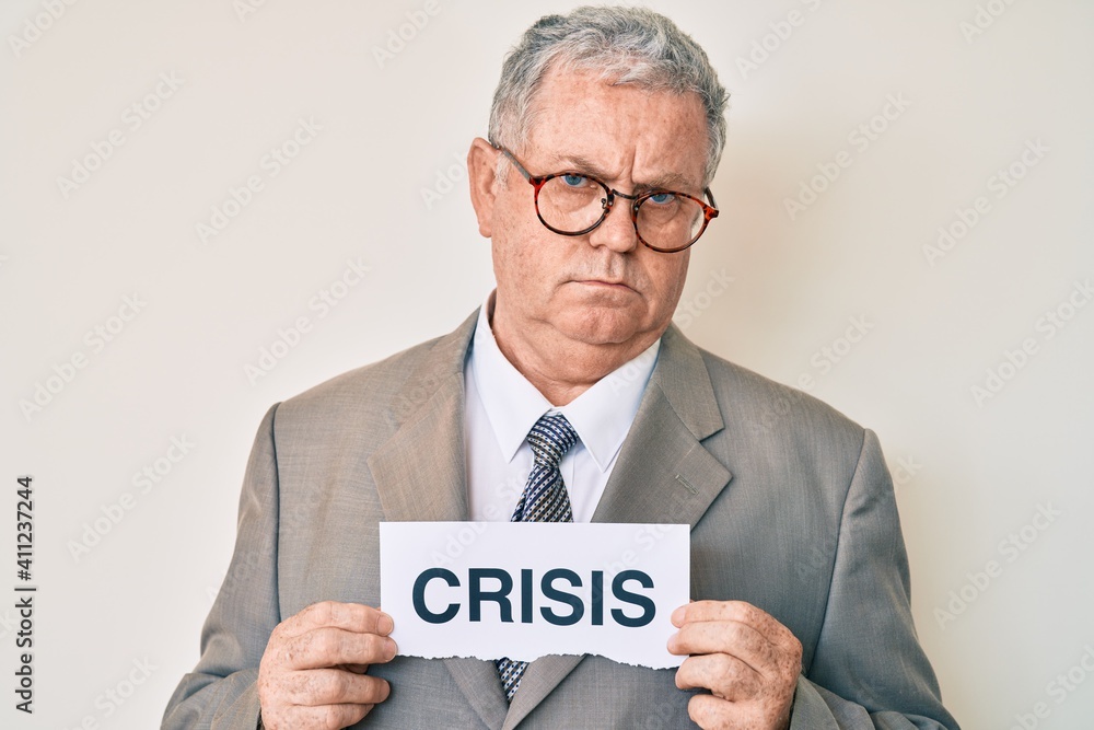 Senior grey-haired man wearing business suit holding crisis paper skeptic and nervous, frowning upset because of problem. negative person. Senior grey-haired man wearing business suit holding crisis paper skeptic and nervous, frowning upset because of problem. negative person.