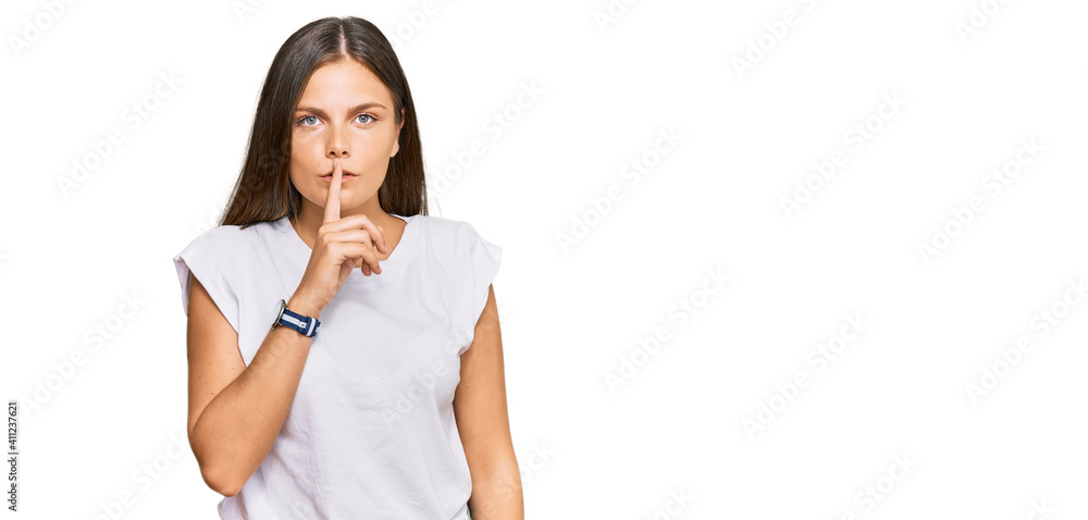 Young caucasian woman wearing casual white tshirt asking to be quiet with finger on lips. silence and secret concept.