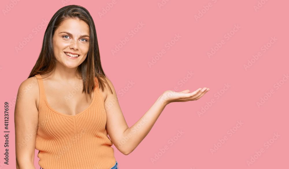 Young caucasian woman wearing casual clothes smiling cheerful presenting and pointing with palm of hand looking at the camera. Young caucasian woman wearing casual clothes smiling cheerful presenting and pointing with palm of hand looking at the camera.