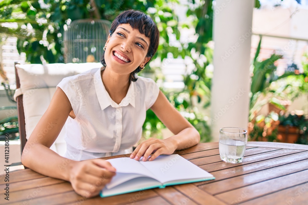 Beautiful woman with short hair sitting at the terrace on a sunny day reading a book Beautiful woman with short hair sitting at the terrace on a sunny day reading a book
