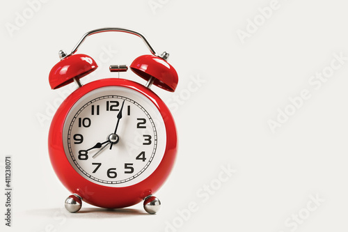 Red retro alarm clock on white table. Copy space.