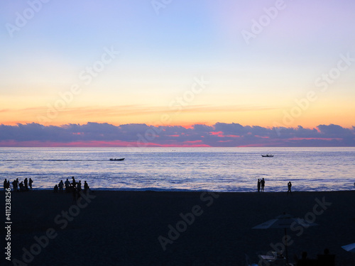 A beautiful pastel coloured sunset over the Pacific Ocean in Peurto Escondito, Mexico, with the silhouettes of people outlined against the water.  Image has copy space. photo