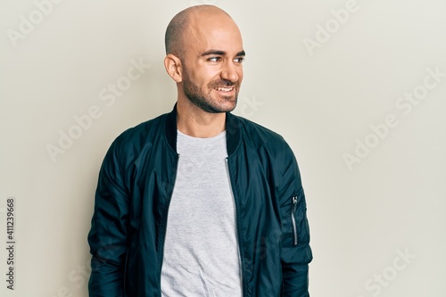 Young hispanic man wearing casual sporty jacket looking to side, relax profile pose with natural face and confident smile.