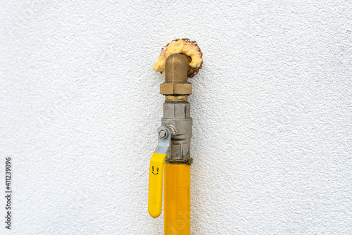 Gas valve located on the facade of the building, supplying gas to the boiler room, with a yellow handle. photo