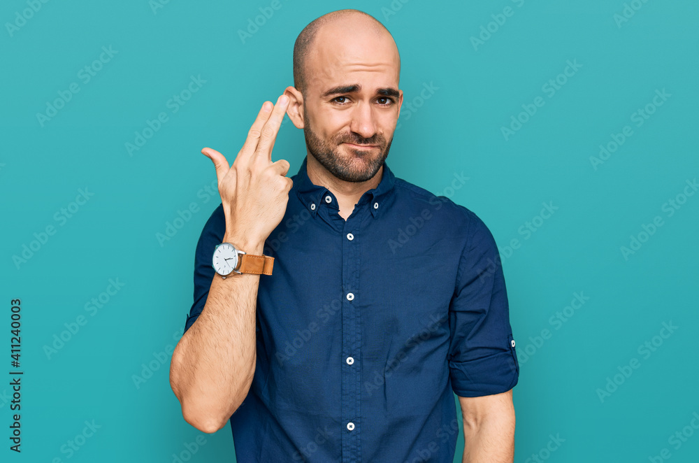 Naklejka premium Young hispanic man wearing casual clothes shooting and killing oneself pointing hand and fingers to head like gun, suicide gesture.