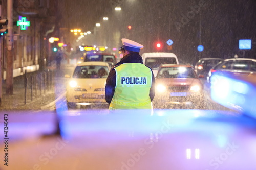 Policjanci ruchu drogowego kierują ruchem w czasie opadów śniegu. 