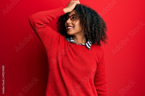 Beautiful african american woman with afro hair wearing sweater and glasses smiling confident touching hair with hand up gesture, posing attractive and fashionable © Krakenimages.com