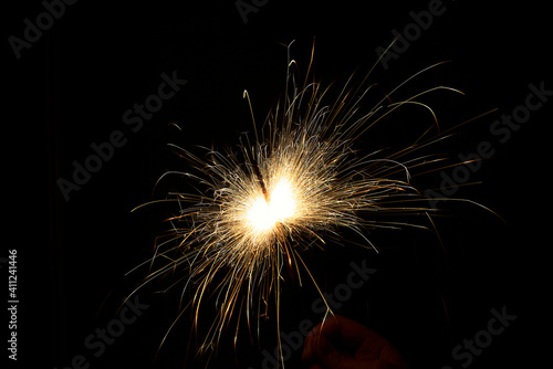 New year sparkler in hands on black background