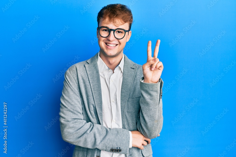 Young caucasian man wearing elegant clothes and glasses smiling with happy face winking at the camera doing victory sign. number two. Young caucasian man wearing elegant clothes and glasses smiling with happy face winking at the camera doing victory sign. number two.