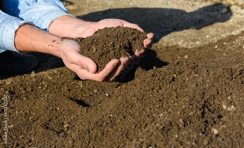 Man's hands hold freshly sifted lawn soil