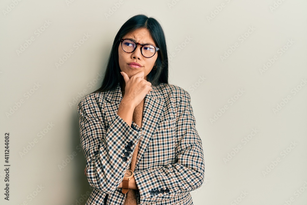 © Krakenimages.com - Young chinese woman wearing business style and glasses thinking worried about a question, concerned and nervous with hand on chin