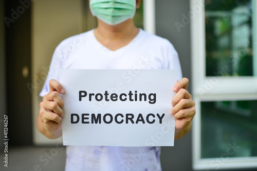 The image of asia man holding a paper with a message saying protecing democracy.  photo