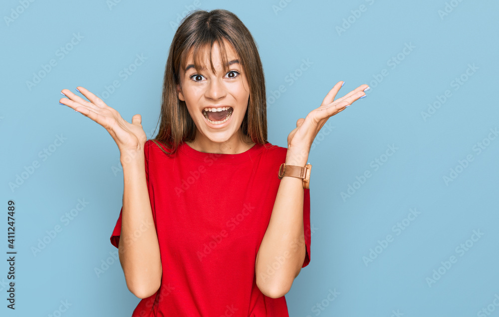Teenager caucasian girl wearing casual red t shirt celebrating crazy and amazed for success with arms raised and open eyes screaming excited. winner concept Teenager caucasian girl wearing casual red t shirt celebrating crazy and amazed for success with arms raised and open eyes screaming excited. winner concept