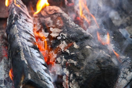 Glowing embers in hot red color, abstract background. The hot embers of burning wood log fire. Firewood burning on grill. Texture fire bonfire embers.