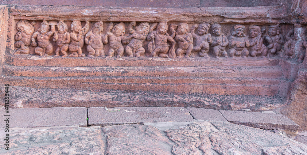 Badami, Karnataka, India - November 7, 2013: Cave temples above Agasthya Lake. Closeup of restone sculpture of row of small human figures dancing and being merry.