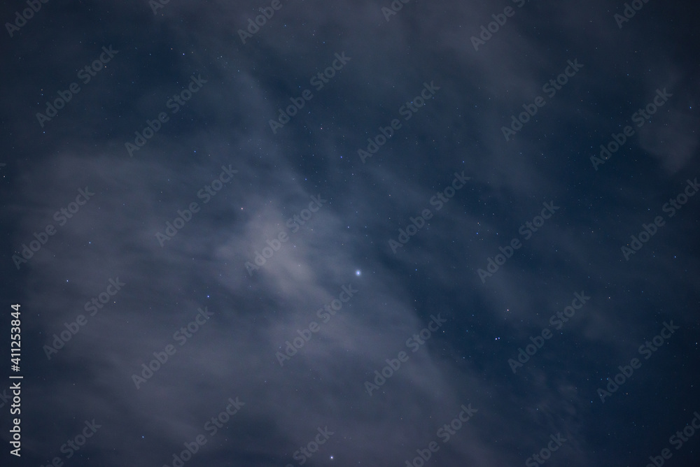 stars among the clouds illuminated by the moonlit sky in the night sky. Stars in the night sky through the clouds on a summer night