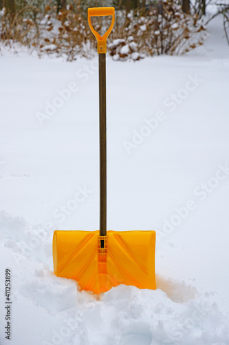 A yellow snow shovel in the snow after a winter storm