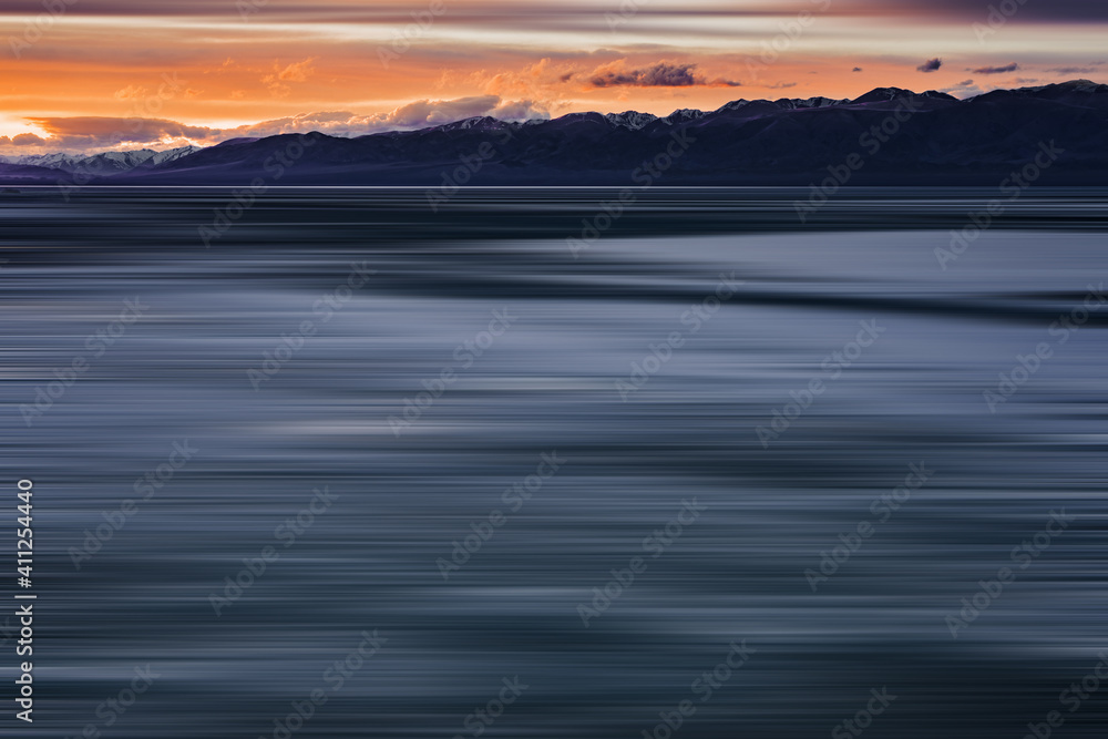 blurred view of plain at root of snow-covered mountains at sunset 