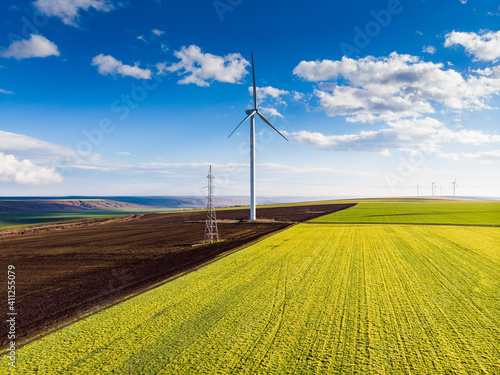 Beautiful bright Landscape with a Windfarm on a sunny day with a sky full of clouds and colorful foreground with green-yellowish grass