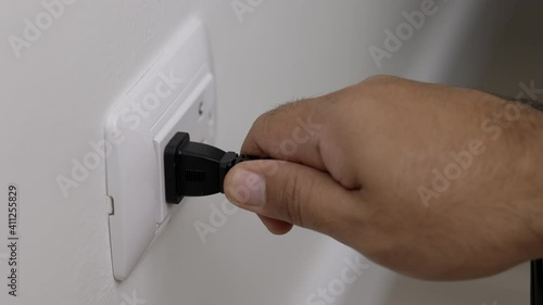 Hand remove Electric plug on socket. Electrical equipment, electrical wires and power strips in the house. Earth Hour saving electrical energy.