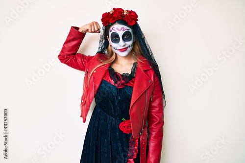 Woman wearing day of the dead costume over white strong person showing arm muscle, confident and proud of power