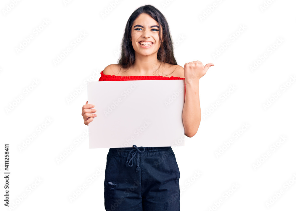 Brunette teenager girl holding blank empty banner screaming proud, celebrating victory and success very excited with raised arms Brunette teenager girl holding blank empty banner screaming proud, celebrating victory and success very excited with raised arms