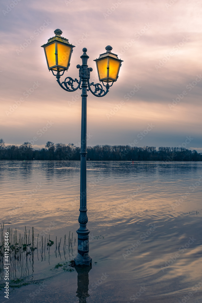 View towards a lantern at high water in the evening light on the promenade in Eltville / Germany on the Rhine