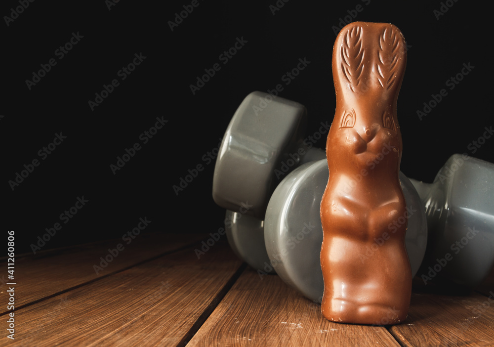 Chocolate Easter bunny with heavy dumbbells on wooden table. Easter fitness  and training composition with copy space. Stock-Foto | Adobe Stock