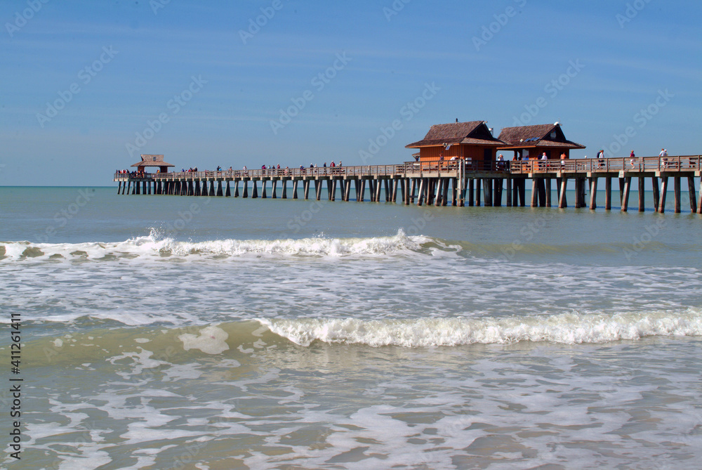 front view, far away of a wooden pier and comercial structures, jutting into the tropical waters, of gulf of Mexico, on sunny morning