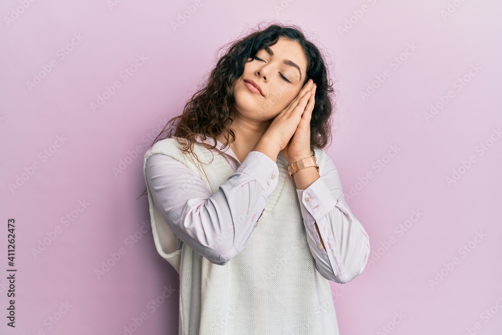 Young brunette woman with curly hair wearing casual clothes sleeping tired dreaming and posing with hands together while smiling with closed eyes. Young brunette woman with curly hair wearing casual clothes sleeping tired dreaming and posing with hands together while smiling with closed eyes.