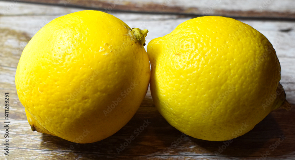 Two lemons isolated on wooden table, fresh fruit