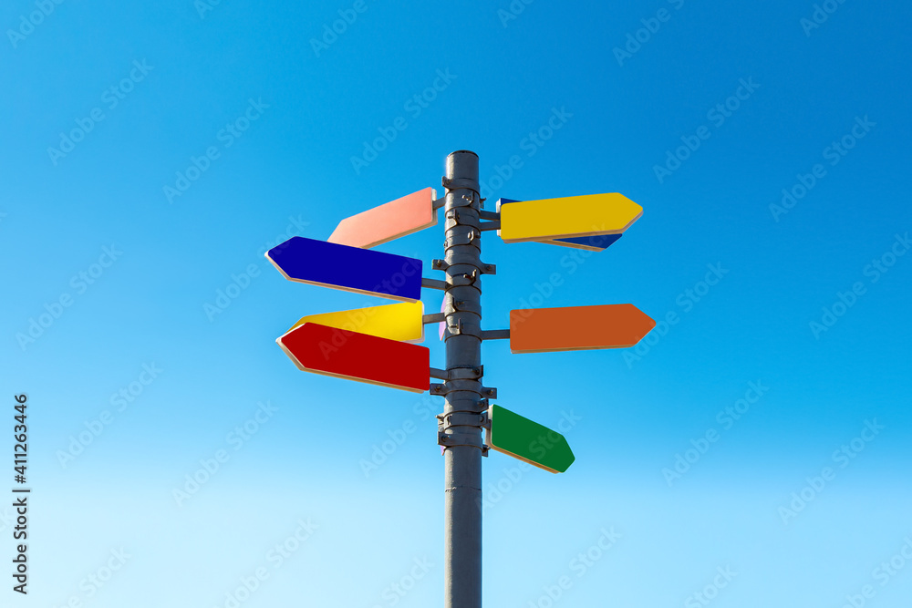 Signpost with bright colored arrows against blue sky Signpost with bright colored arrows against blue sky