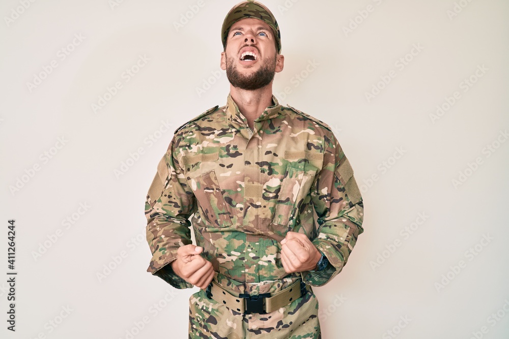 Young caucasian man wearing camouflage army uniform angry and mad screaming frustrated and furious, shouting with anger. rage and aggressive concept.