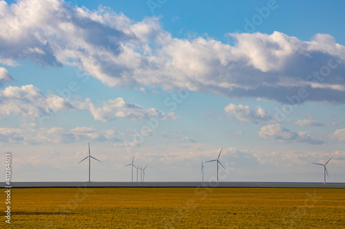 Beautiful bright Landscape with a Windfarm on a sunny day with a sky full of clouds and colorful foreground with green-yellowish grass