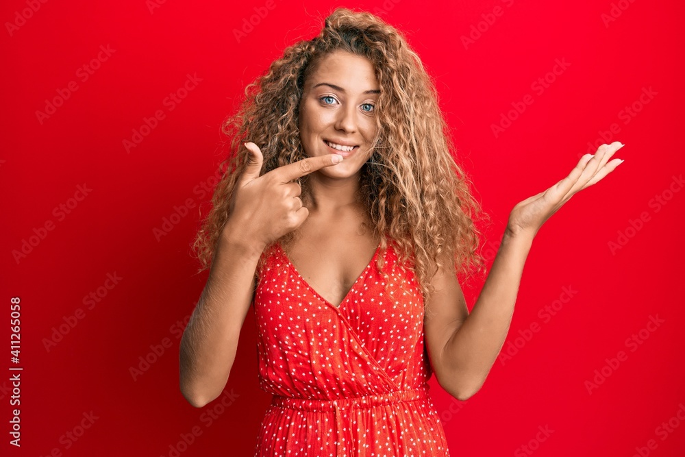 Fototapeta premium Beautiful caucasian teenager girl wearing summer dress amazed and smiling to the camera while presenting with hand and pointing with finger.