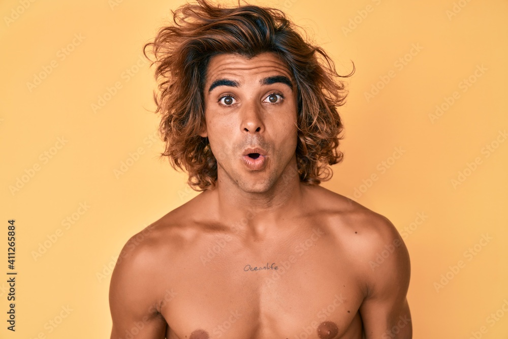 Young hispanic man standing shirtless scared and amazed with open mouth for surprise, disbelief face Young hispanic man standing shirtless scared and amazed with open mouth for surprise, disbelief face