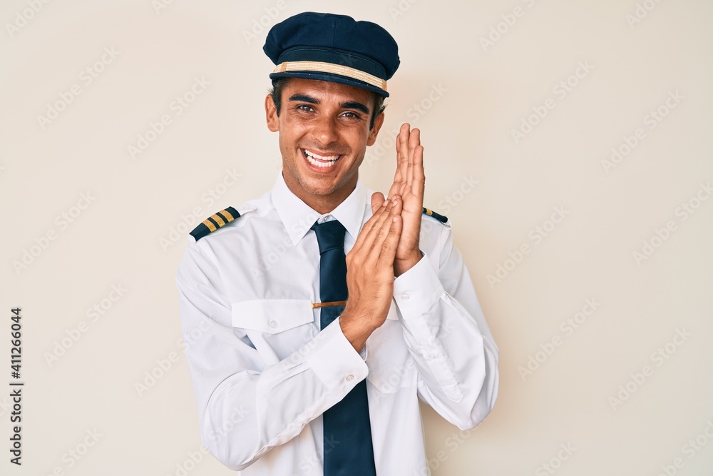 Young hispanic man wearing airplane pilot uniform clapping and applauding happy and joyful, smiling proud hands together Young hispanic man wearing airplane pilot uniform clapping and applauding happy and joyful, smiling proud hands together