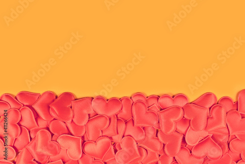 Red heart shaped confetti hearts at borrom of orange background with empty copy space photo