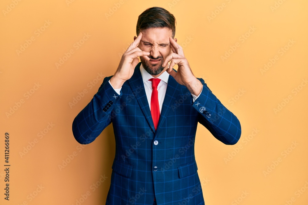 Handsome man with beard wearing business suit and tie suffering from headache desperate and stressed because pain and migraine. hands on head. Handsome man with beard wearing business suit and tie suffering from headache desperate and stressed because pain and migraine. hands on head.